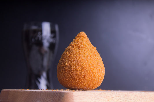 Photo of a single Coxinhas, a tear shaped breaded food item. 