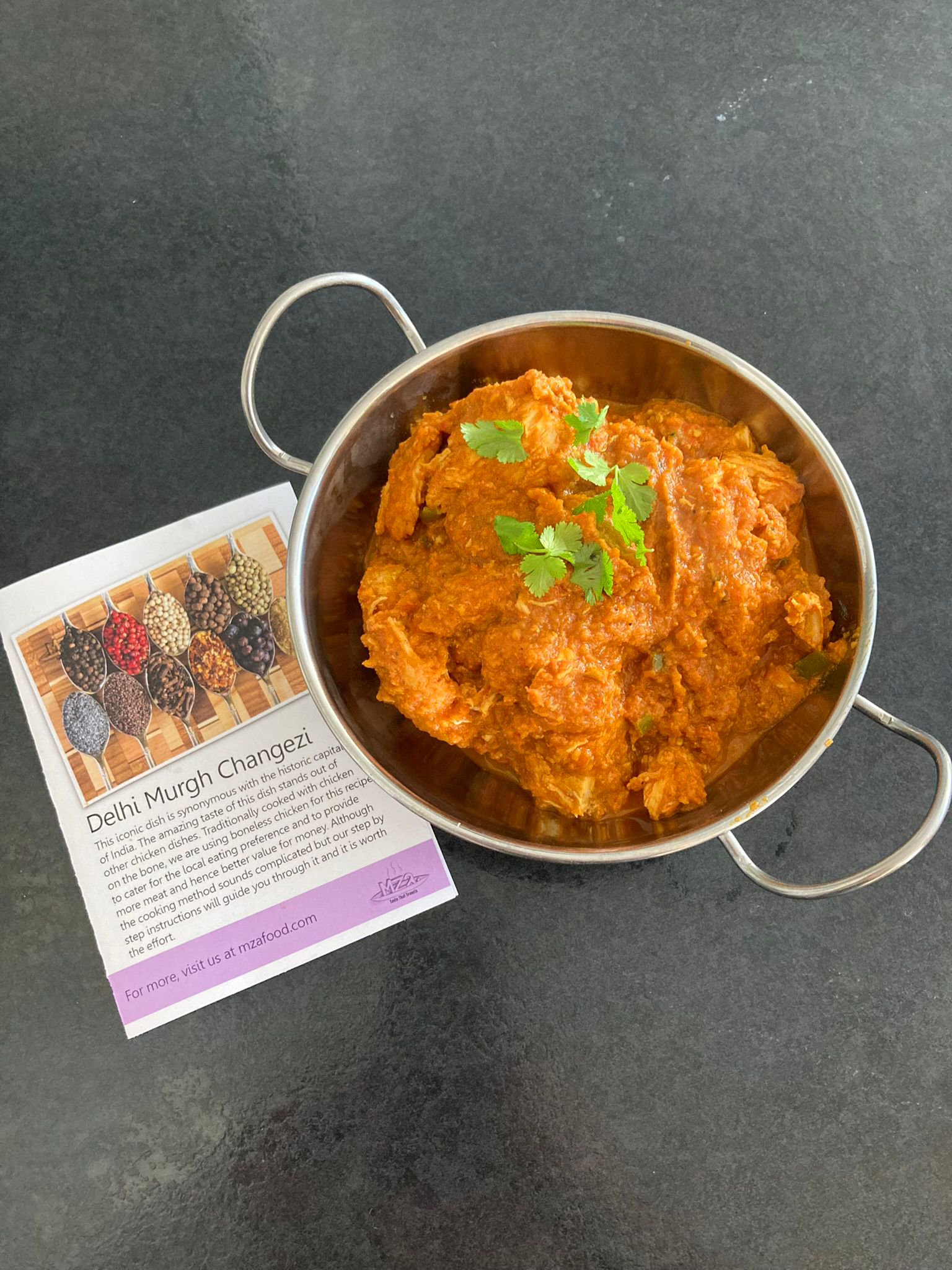 Photo of Delhi murgh changezi in a balti dish next to its recipe card.