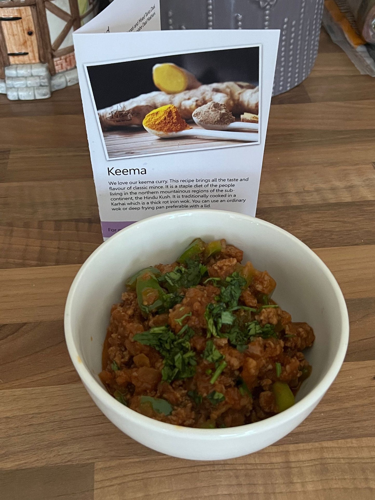 Keema in a white bowl with the recipe card in the background. 