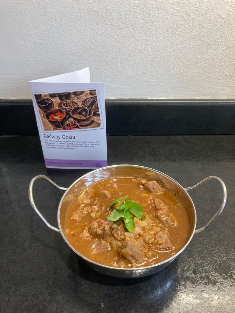 Photo of railway gosht in a balti dish with its recipe card behind it. 