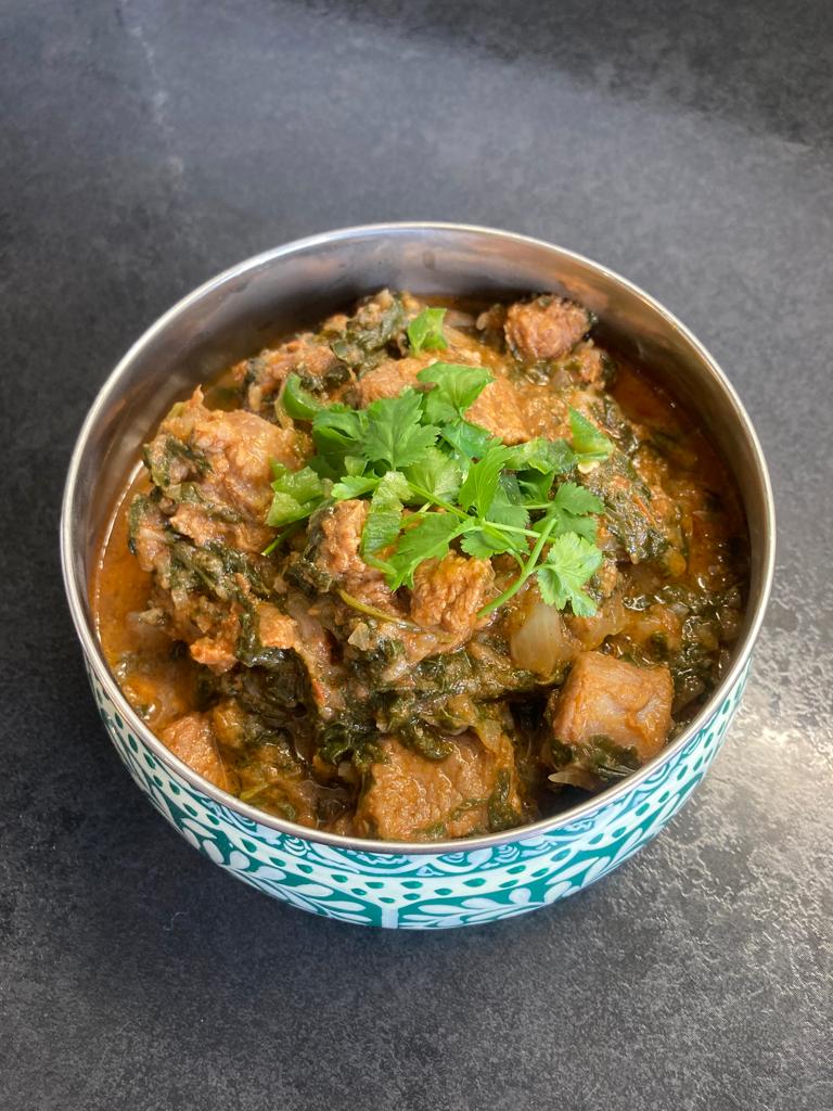 Photo of saag gosht in a blue bowl.