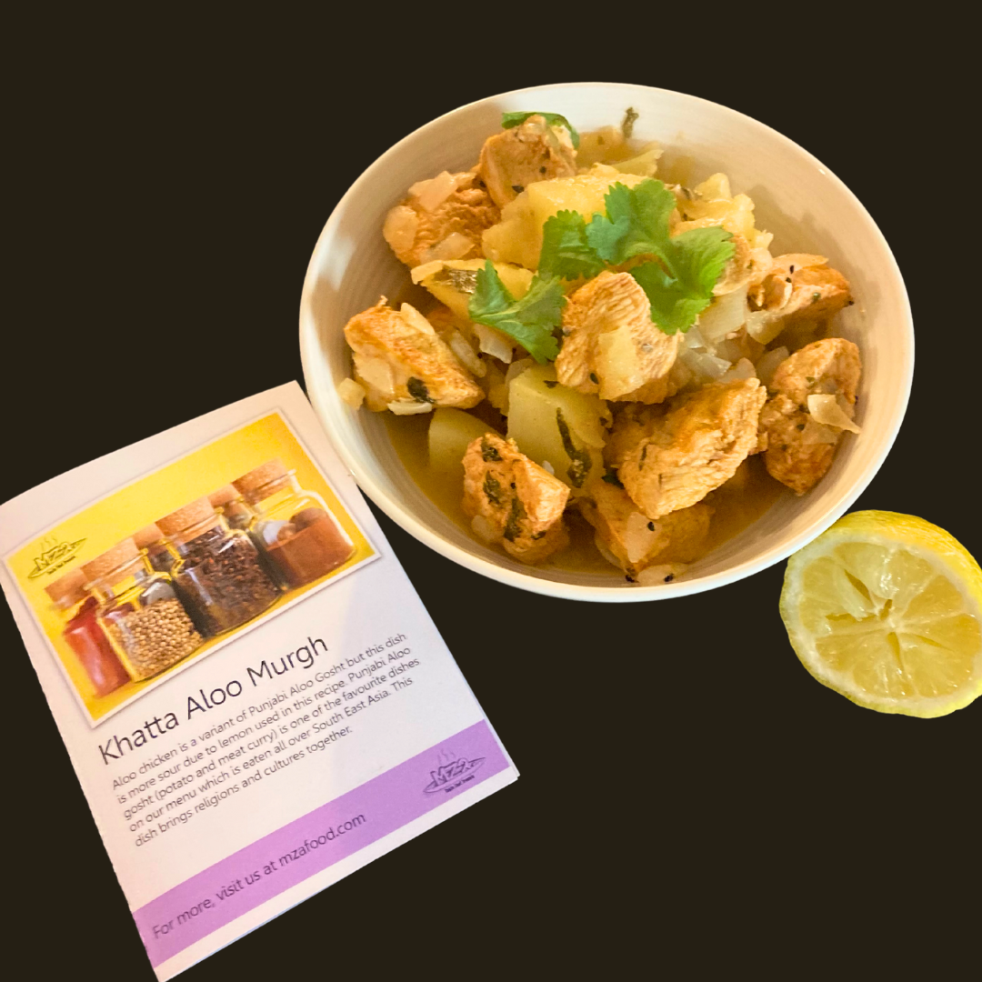 Photo of Khatta Aloo Murgh in a bowl with a slice of lemon on the side. next to it is the recipe card for this dish.