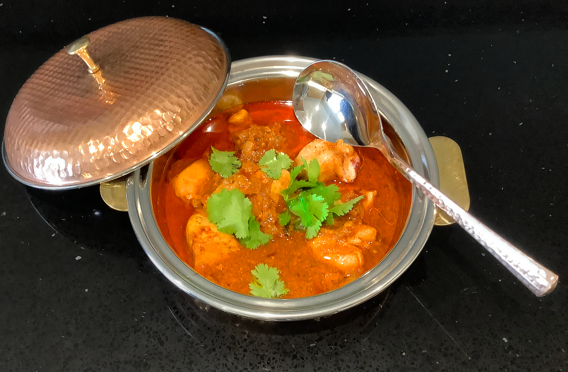 Punjabi aloo gosht in a copper coloured metallic bowl. 